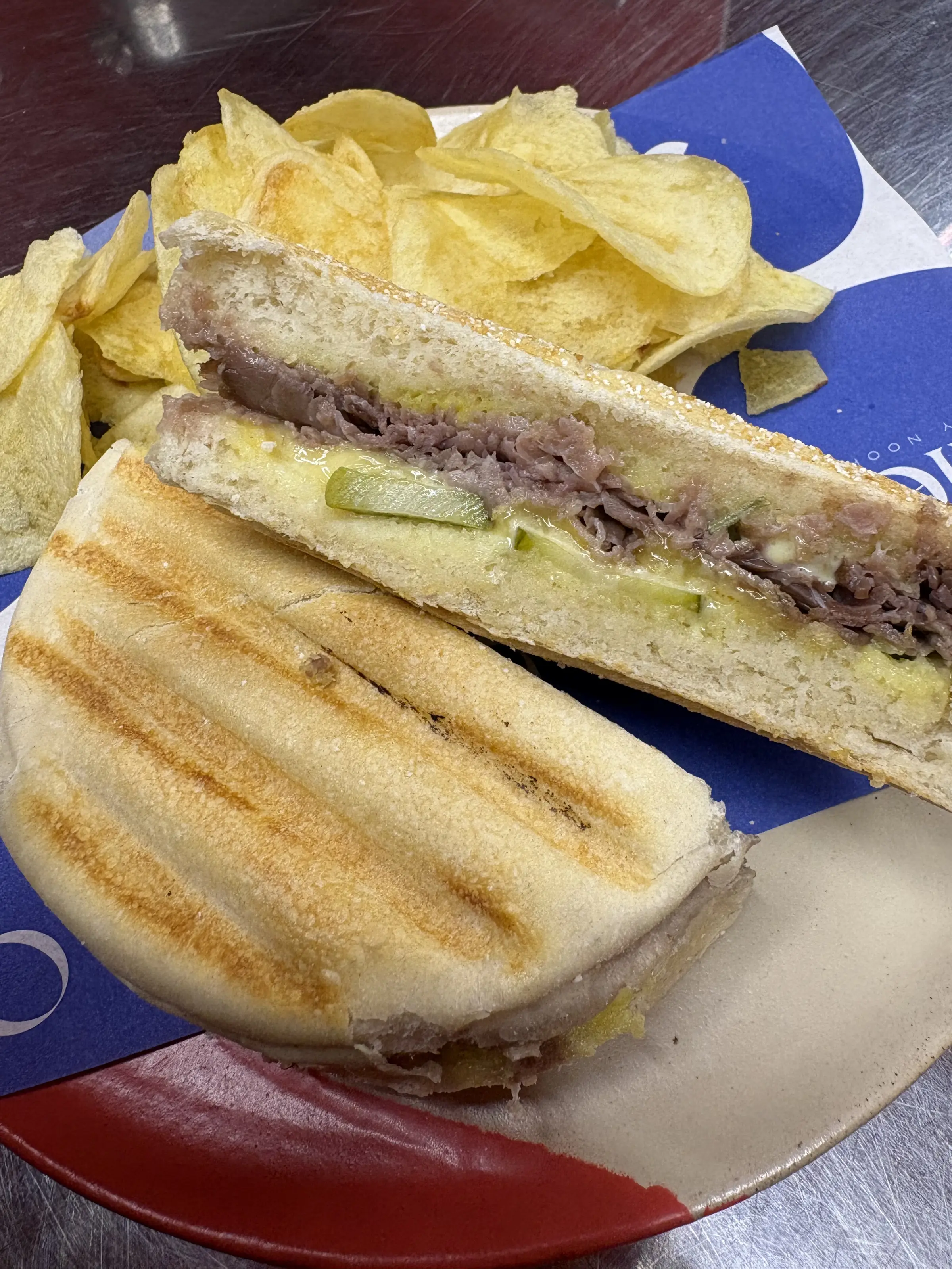 Sandwich Roast Beef Ollie cortado por la mitad, con papas